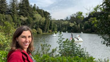 mulher sorrindo em frente a lago de parque verde ao redor