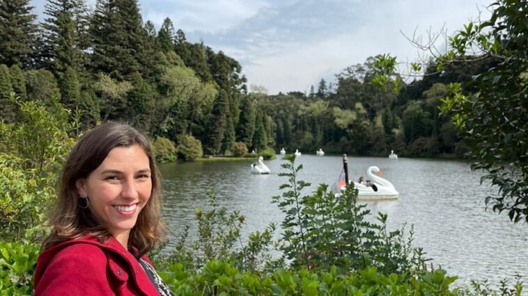 mulher sorrindo em frente a lago de parque verde ao redor