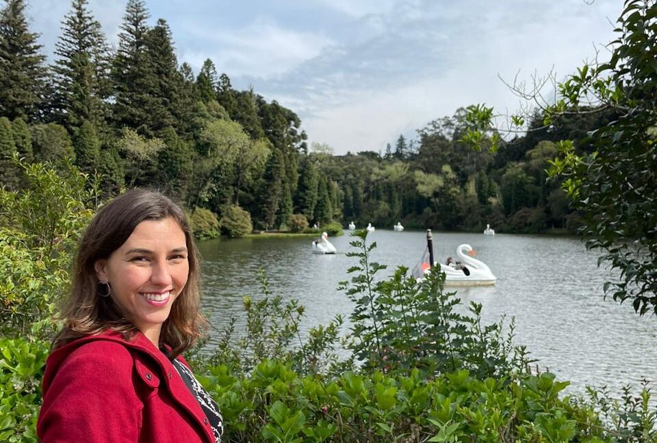 mulher sorrindo em frente a lago de parque verde ao redor