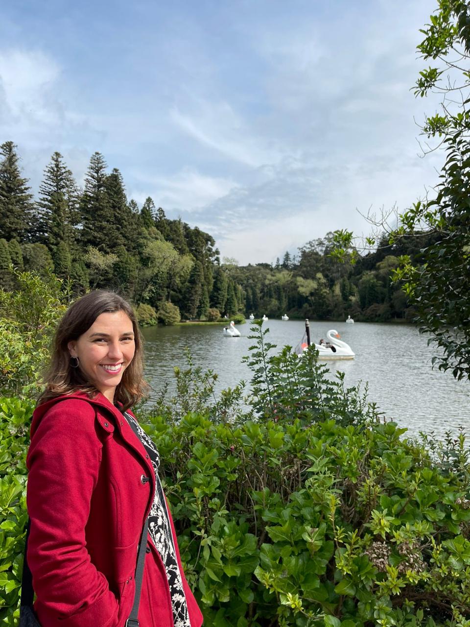 mulher sorrindo em frente a lago de parque verde ao redor