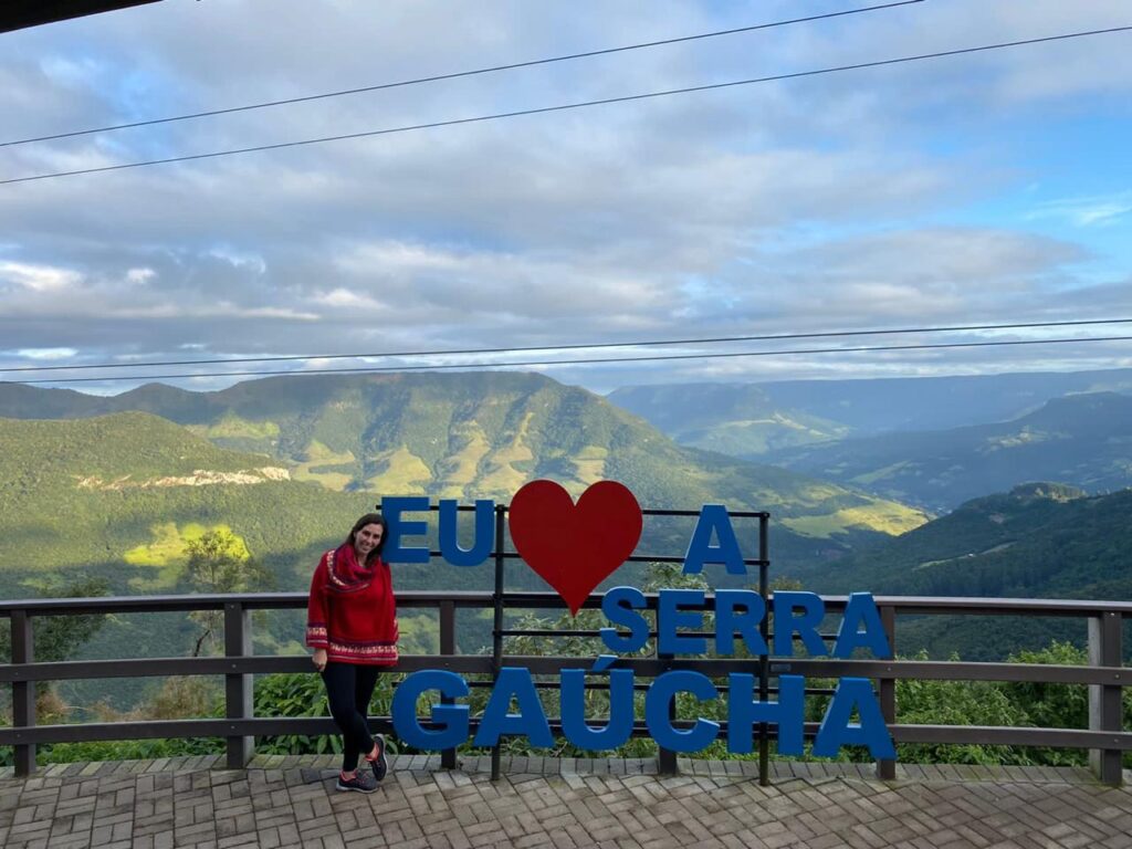 mulher ao lado de letreiro com serra ao fundo