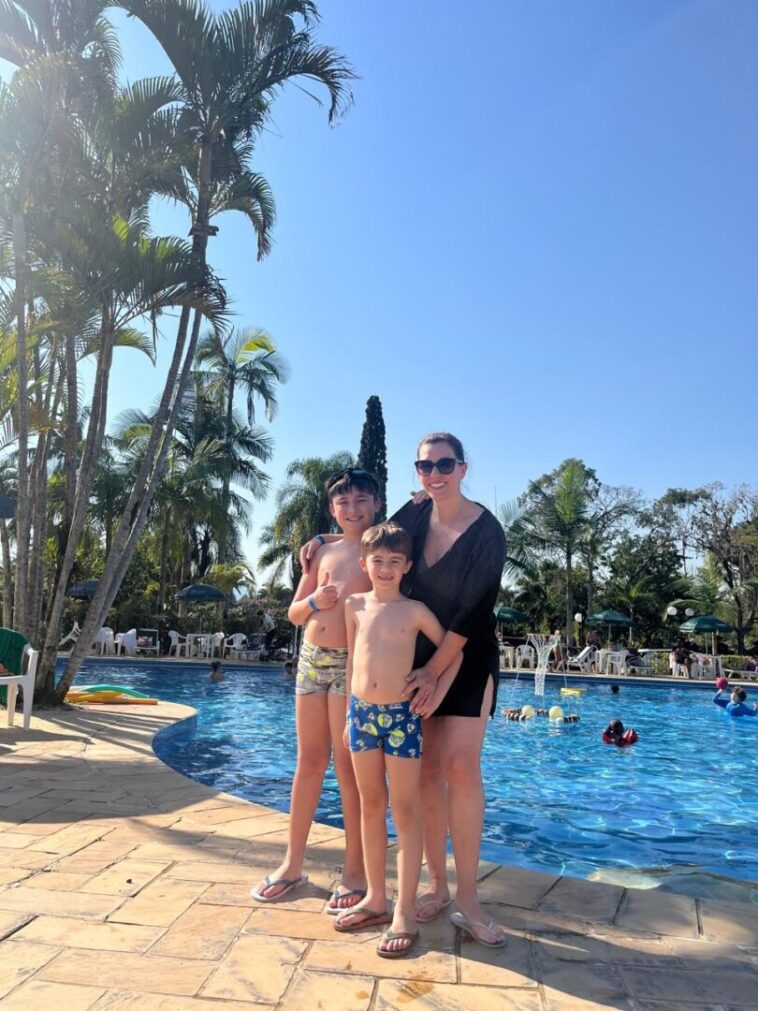 mulher com dois filhos e piscina ao fundo