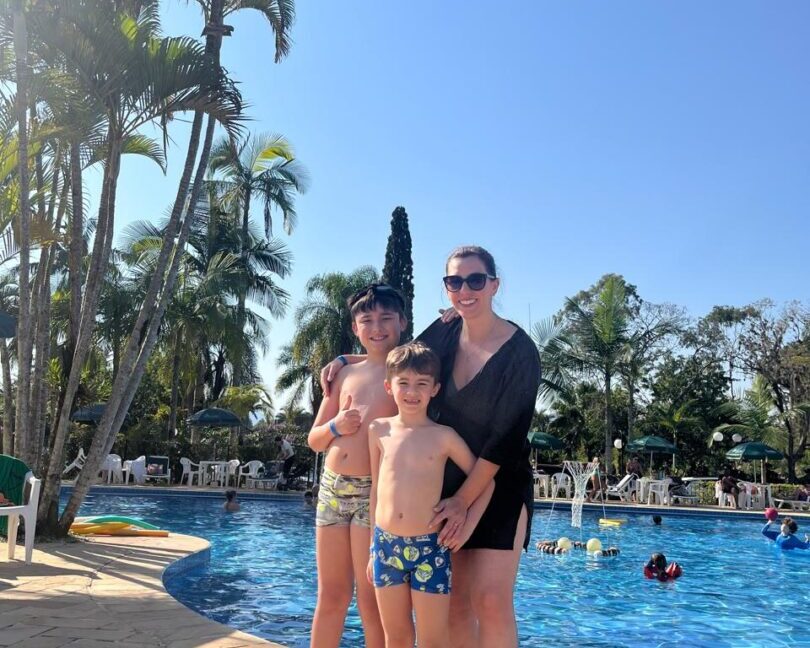 mulher com dois filhos e piscina ao fundo