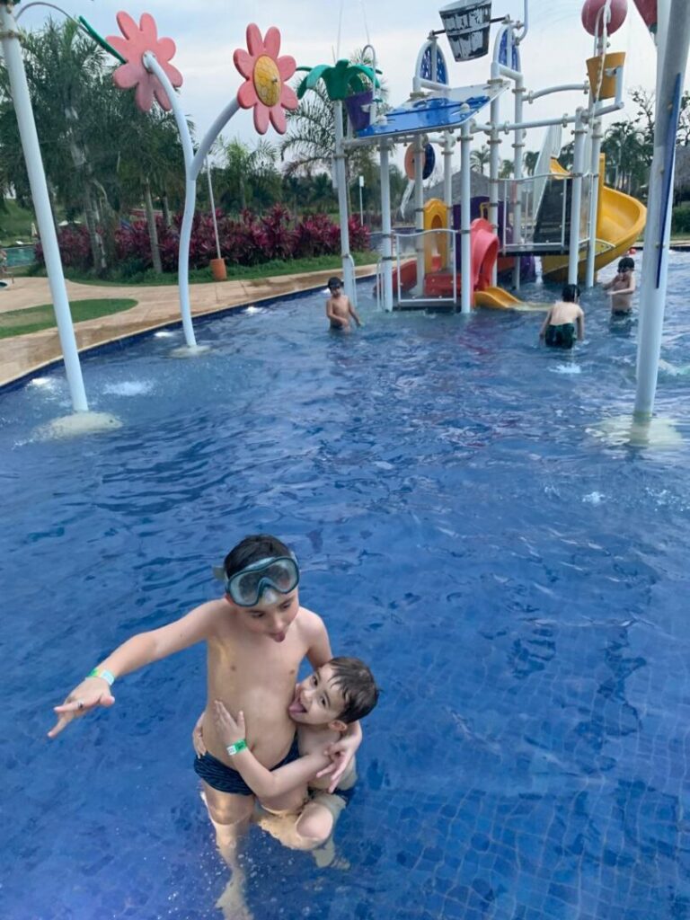 dois meninos brincando em piscina com playground aquático