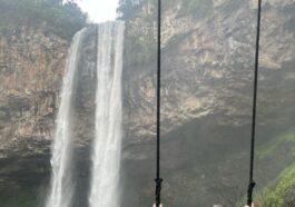 mulher em balanço em frente a cachoeira