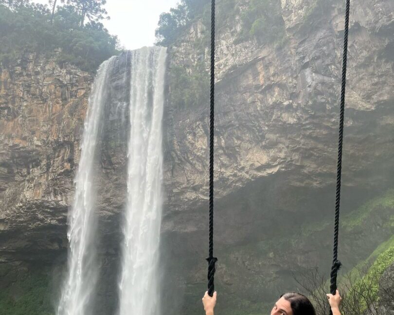 mulher em balanço em frente a cachoeira