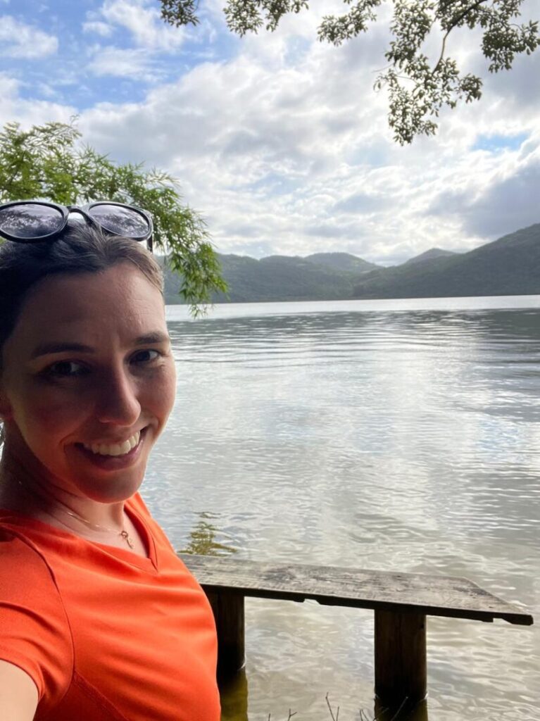 Selfie de mulher com lagoa ao fundo.