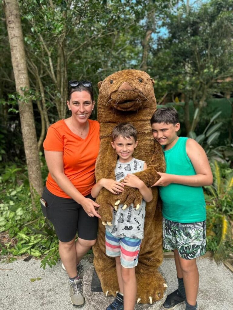 mãe e dois filhos com mascote de lontra