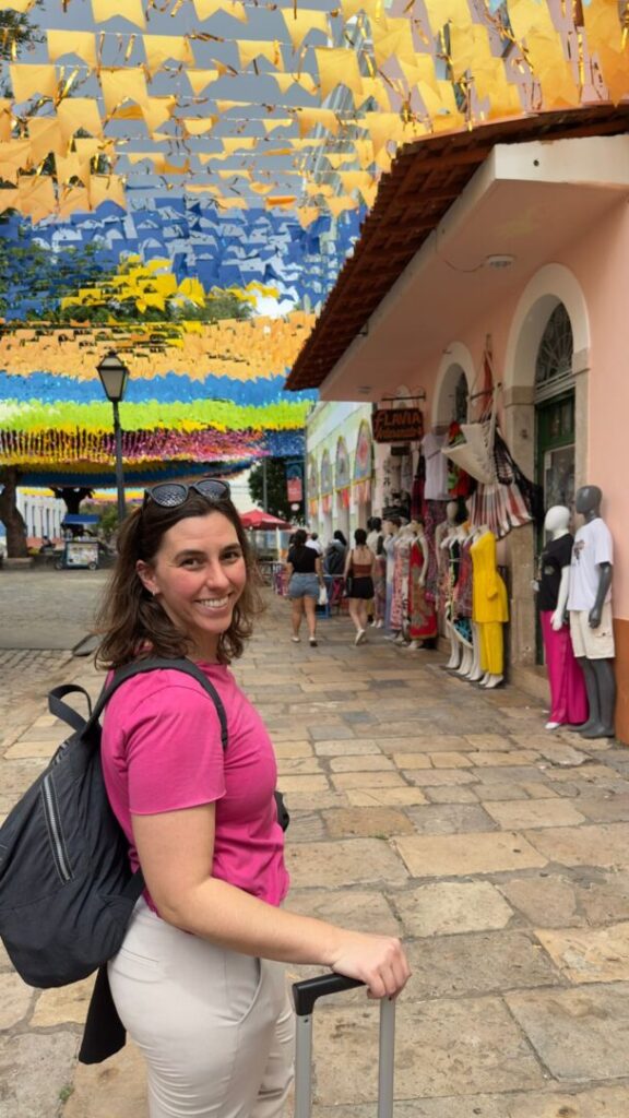 mulher sorrindo em centrinho histórico com bandeirinhas penduradas