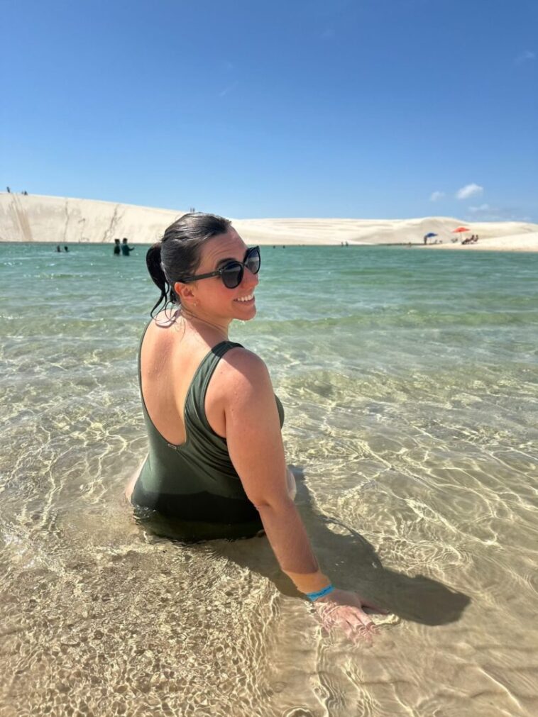 mulher sentada de costas na beira de lagoa dos lençóis maranhenses