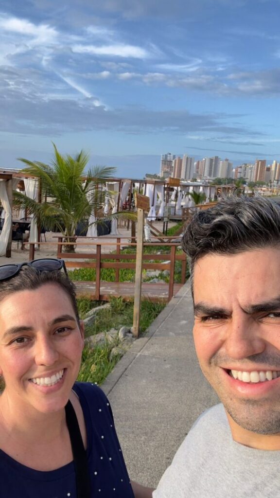 Selfie de casal com gazebos no fundo na beira da praia