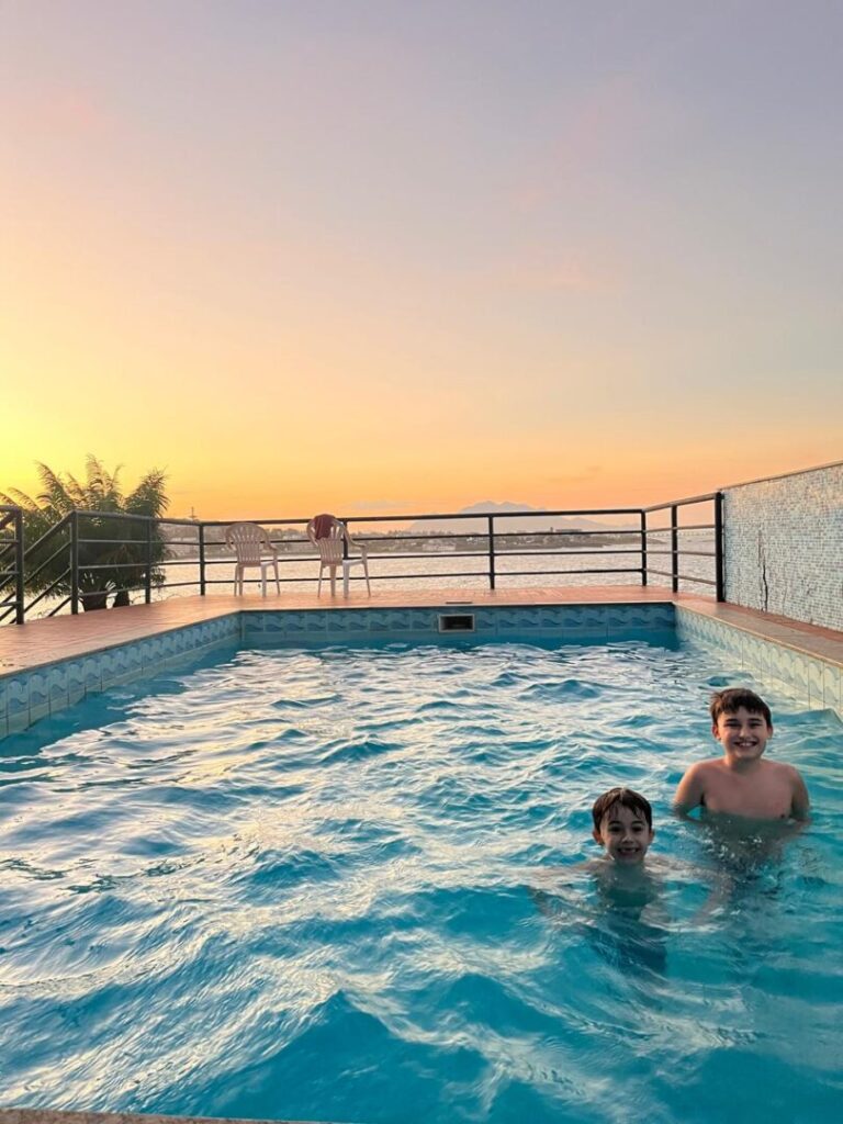 meninos em piscina com pôr do sol ao fundo.