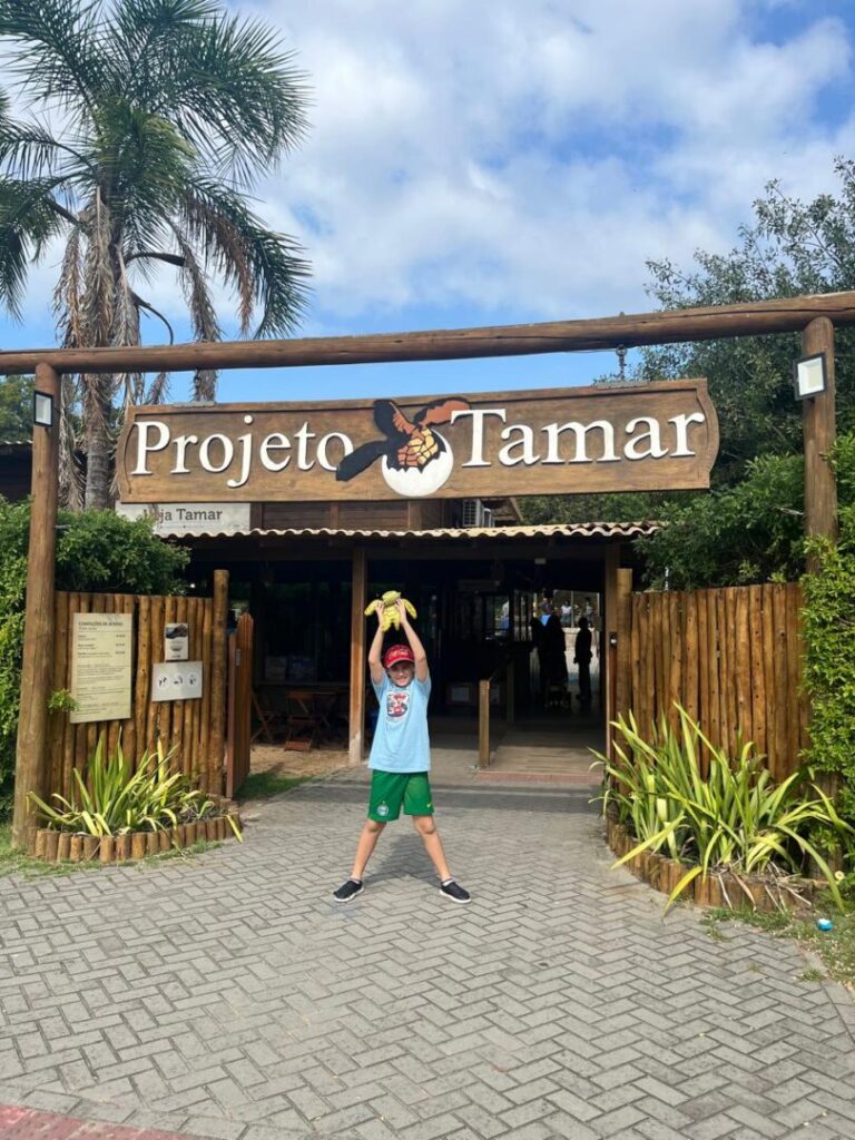 menino em frente a fachada do projeto tamar