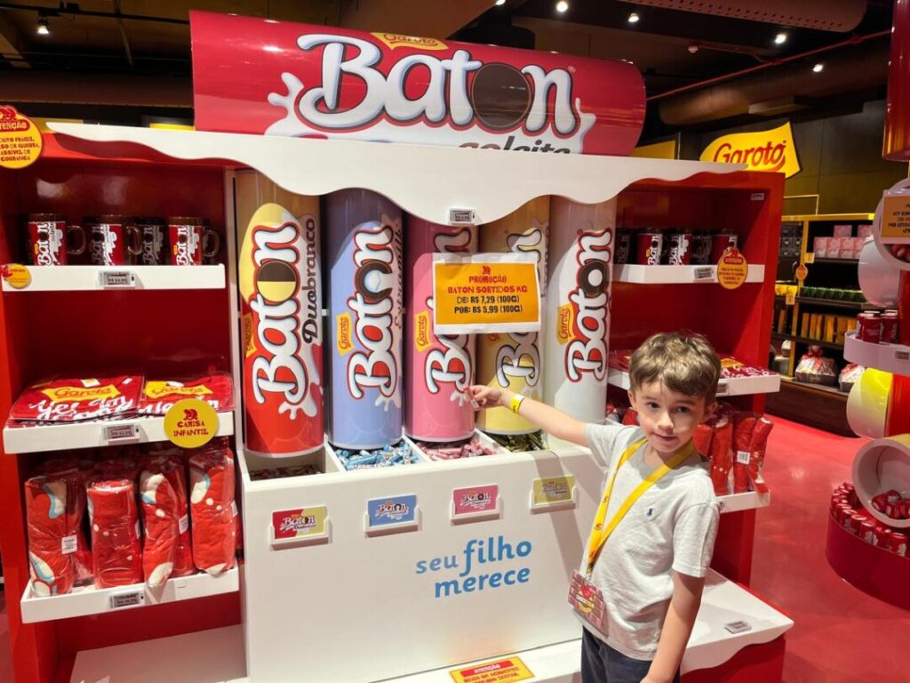 menino em frente a expositor de chocolates