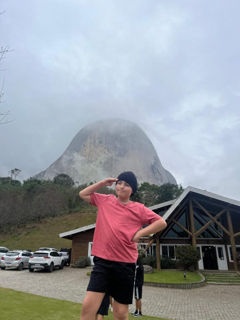 menino em frente a grande pedra de montanha