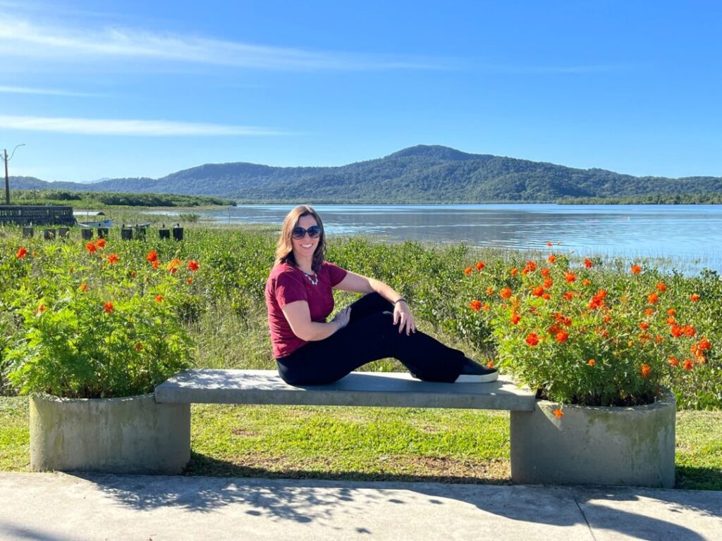 mulher sentada com flores e baía ao fundo com mar