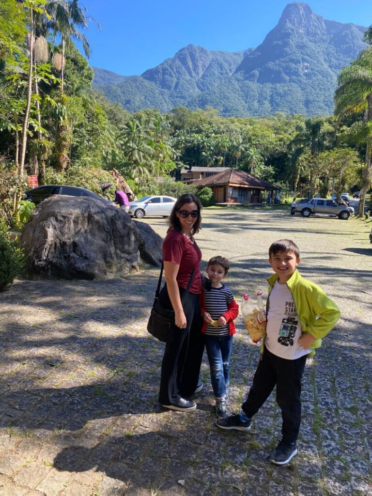 mãe e dois meninos com vista de serra ao fundo.