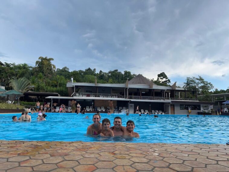 familia de pai, mãe e dois meninos dentro de grande piscina de parque aquático