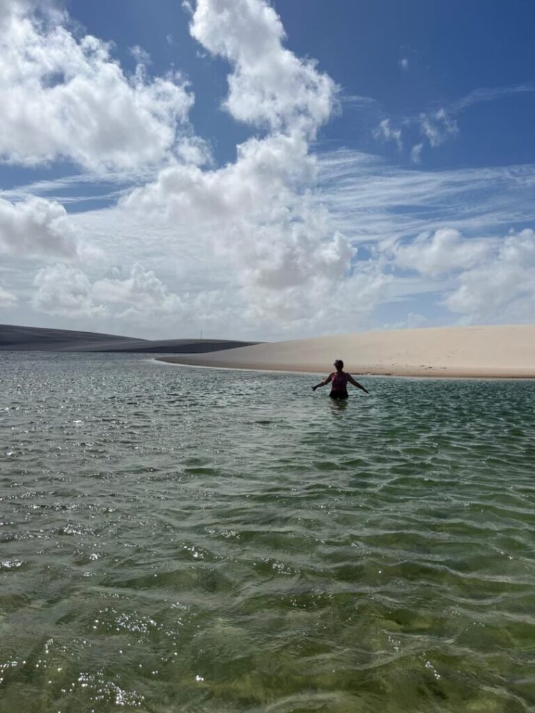 mulher dentro de lagoa e duna no fundo