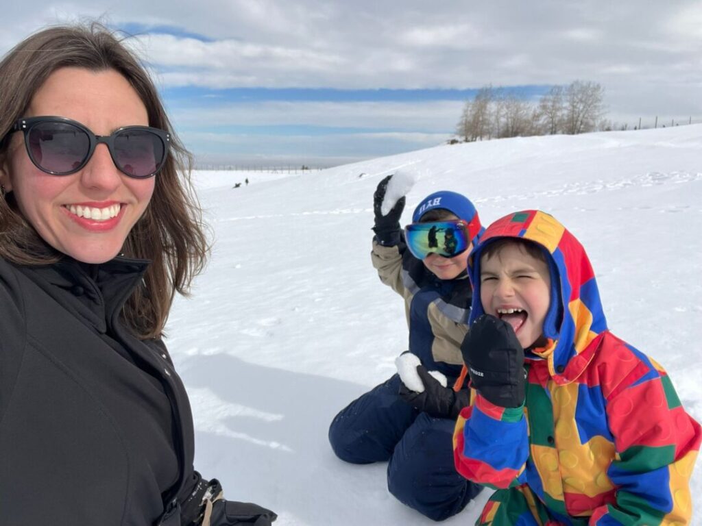 mãe e dois meninos sentados na neve