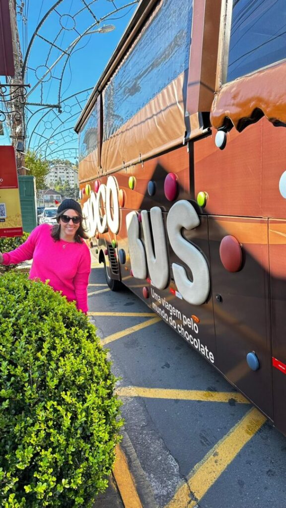 mulher ao lado de ônibus temático de chocolate