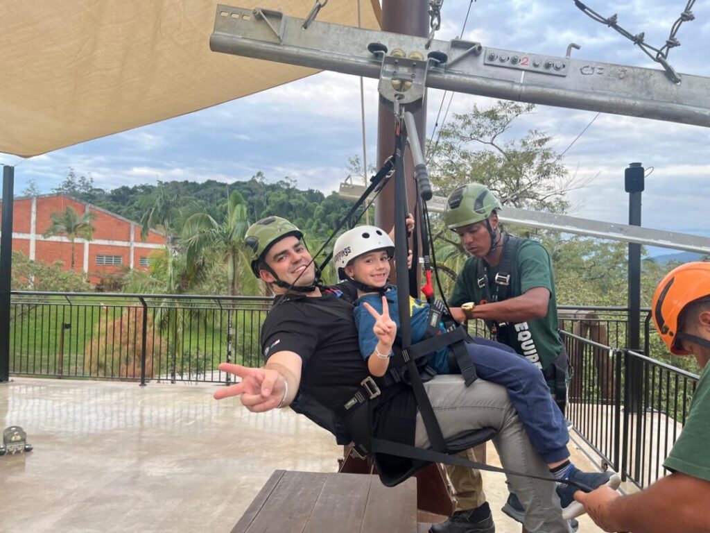 homem e menino sentados em equipamento de tirolesa