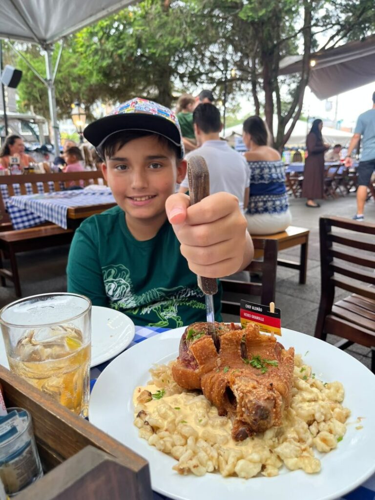Menino segurando faca em prato de comida alemã